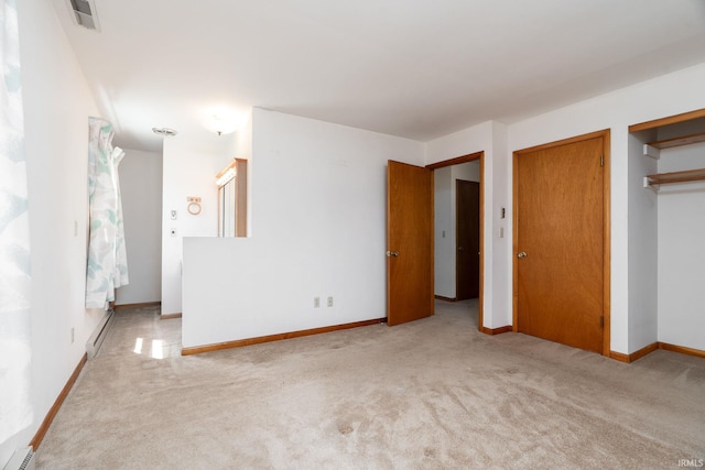 unfurnished bedroom with carpet flooring, a baseboard heating unit, and visible vents
