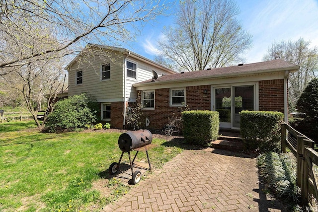 rear view of property featuring a yard, entry steps, and brick siding