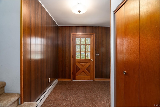 entryway featuring wood walls, a baseboard radiator, stairway, and carpet flooring