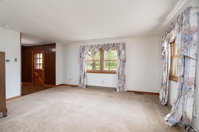 unfurnished room featuring a healthy amount of sunlight, baseboards, visible vents, and carpet floors