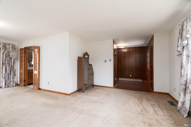 empty room with visible vents, baseboard heating, carpet, and baseboards