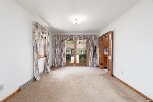 unfurnished room featuring a baseboard heating unit, carpet, and baseboards