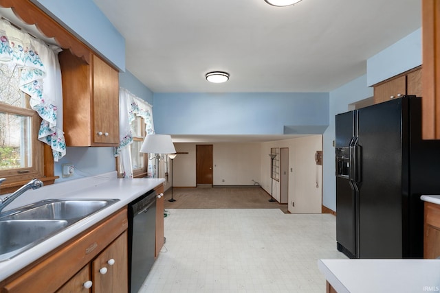 kitchen featuring a sink, brown cabinets, light countertops, black appliances, and baseboards