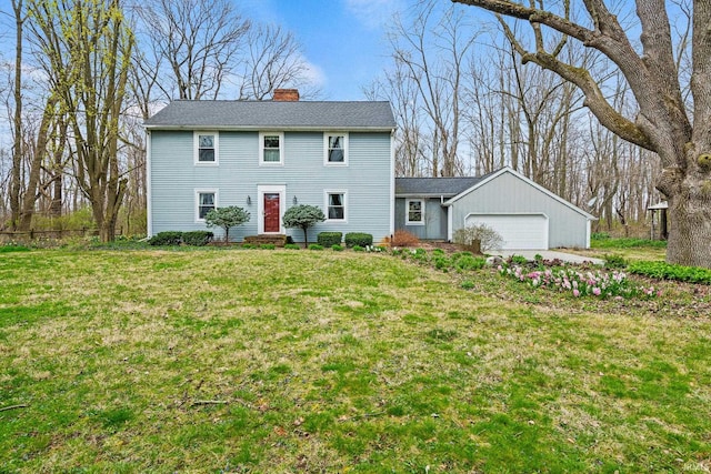 colonial-style house featuring a chimney, entry steps, a front lawn, and a garage
