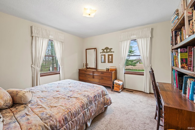 bedroom featuring carpet, visible vents, and a textured ceiling
