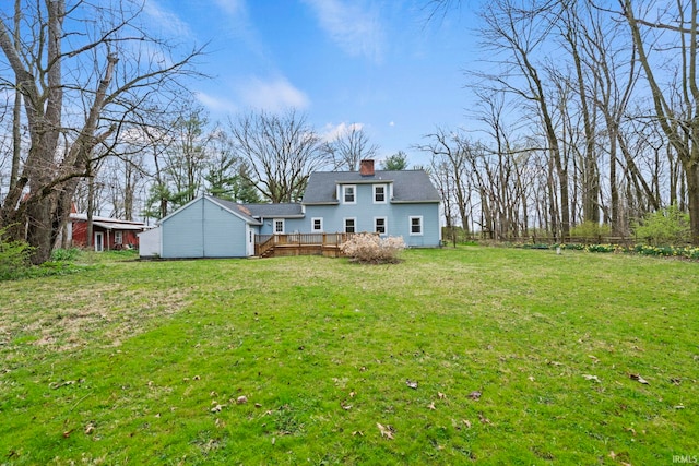 back of house featuring a wooden deck, a yard, and a chimney