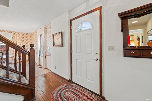 foyer with stairway, a healthy amount of sunlight, baseboards, wallpapered walls, and hardwood / wood-style flooring