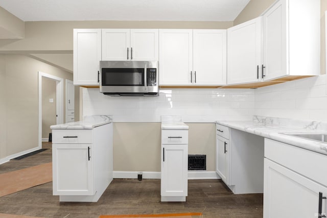 4121 Smith St, Fort Wayne, IN 46806 - kitchen featuring dark wood-style floors, white cabinets, backsplash, and stainless steel microwave