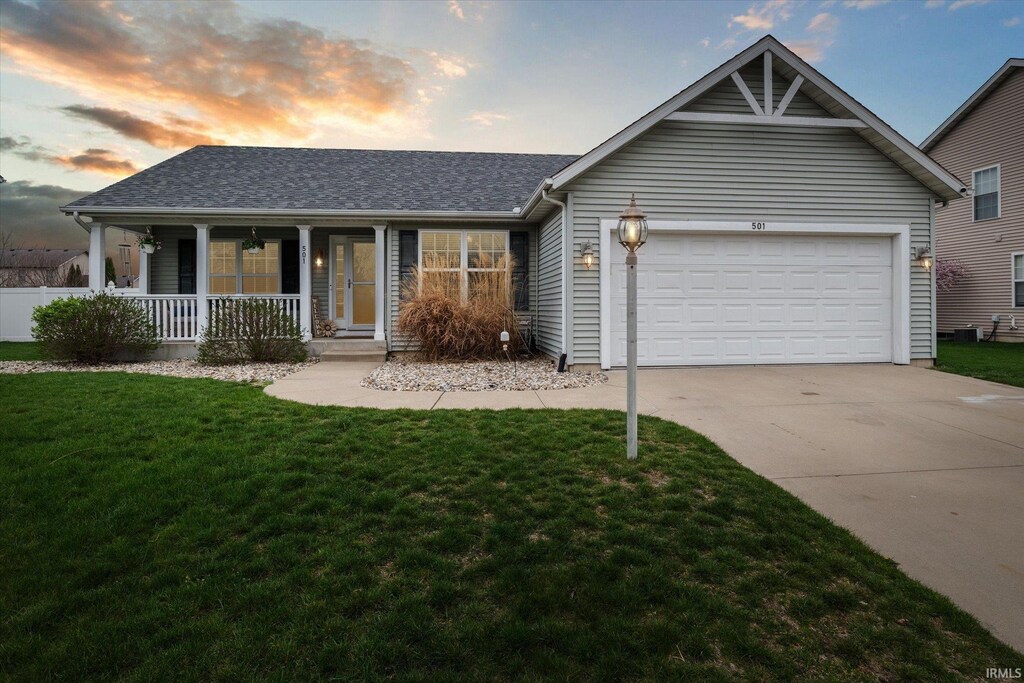 single story home featuring a front yard, a garage, covered porch, driveway, and roof with shingles