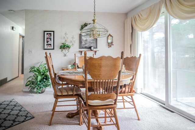dining area featuring light colored carpet, visible vents, and a notable chandelier