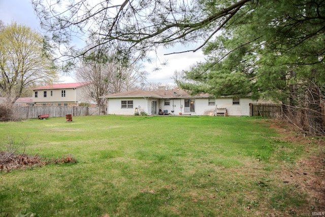 back of house with a lawn and a fenced backyard