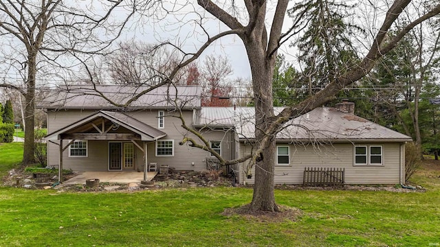 back of property with a lawn, a chimney, and a patio area
