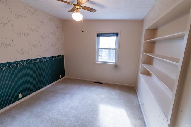 spare room with a ceiling fan, visible vents, wallpapered walls, and carpet floors