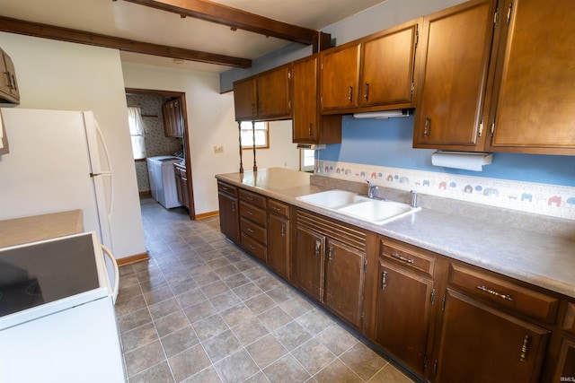 kitchen featuring a sink, beam ceiling, washer / dryer, light countertops, and freestanding refrigerator