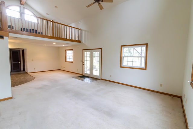 unfurnished living room with a ceiling fan, high vaulted ceiling, carpet floors, and baseboards