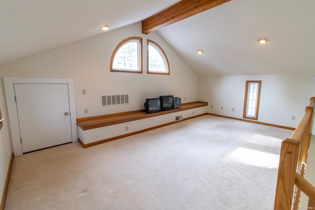 additional living space with baseboards, visible vents, vaulted ceiling with beams, and light colored carpet