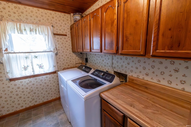 washroom featuring wood ceiling, wallpapered walls, cabinet space, baseboards, and washer and clothes dryer