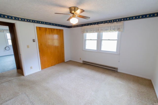 unfurnished bedroom with carpet flooring, ceiling fan, a baseboard heating unit, baseboards, and a closet