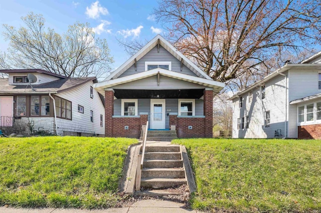 bungalow-style house featuring a porch, brick siding, and a front lawn