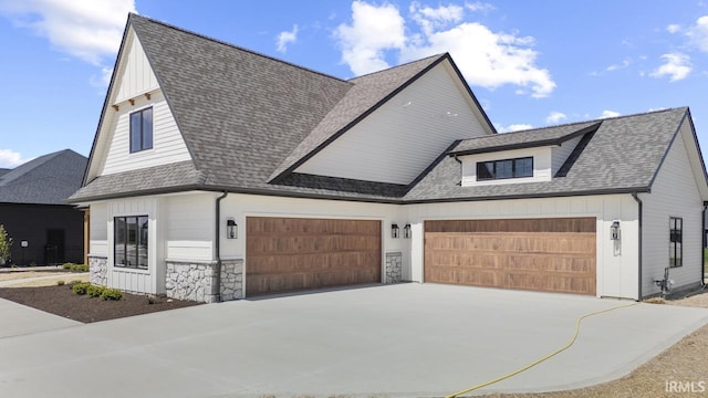 12274 Rain Lily Ct, Fort Wayne, IN 46814 - view of front of property with board and batten siding, driveway, roof with shingles, a garage, and stone siding