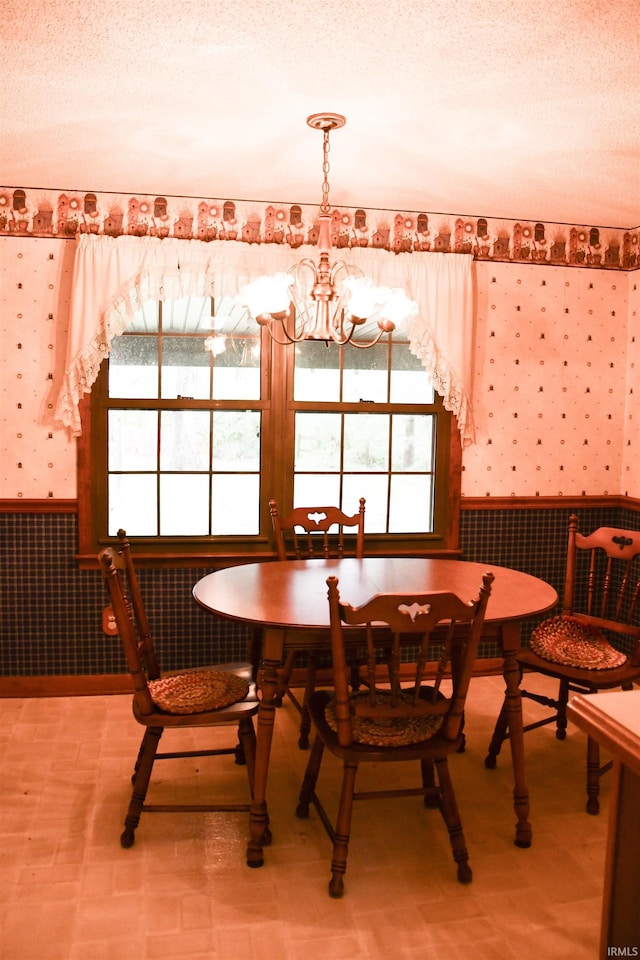 dining room with a wealth of natural light, wallpapered walls, wainscoting, and an inviting chandelier