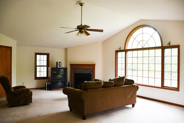 carpeted living area with a tiled fireplace, a ceiling fan, vaulted ceiling, and baseboards