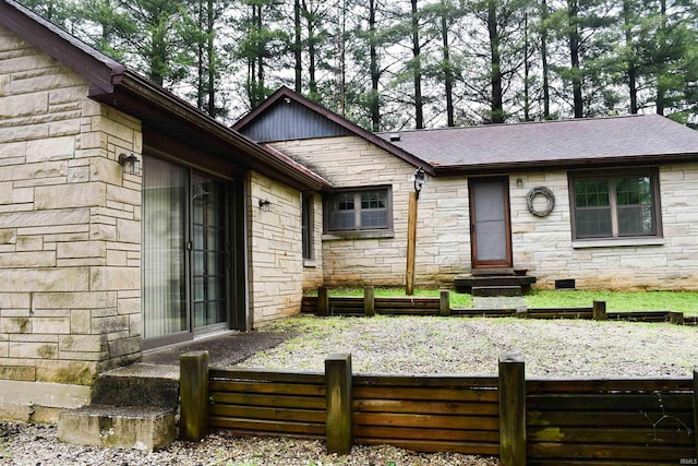 view of front of home featuring entry steps, stone siding, fence private yard, and roof with shingles