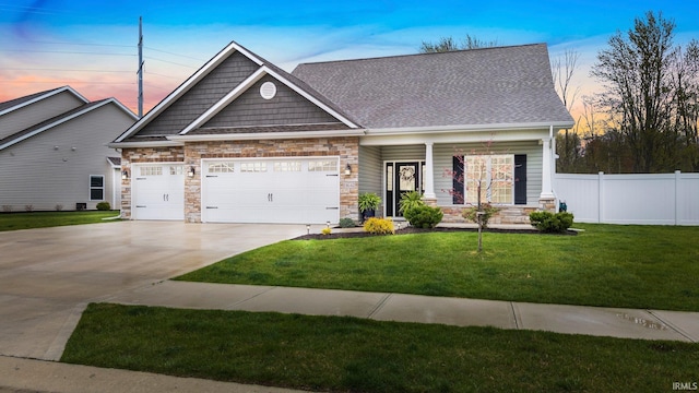 craftsman-style home featuring fence, driveway, stone siding, a front lawn, and an attached garage