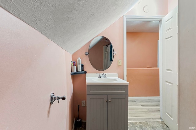 bathroom featuring a textured ceiling, lofted ceiling, and vanity
