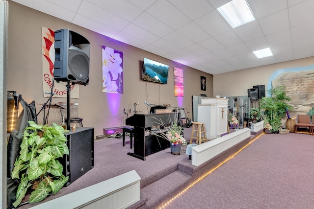 carpeted living area with a paneled ceiling