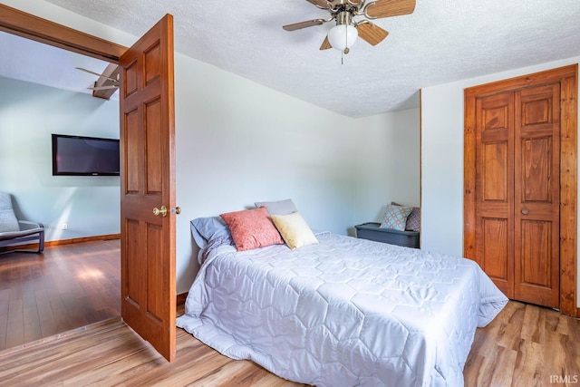 bedroom featuring wood finished floors, a textured ceiling, baseboards, and ceiling fan