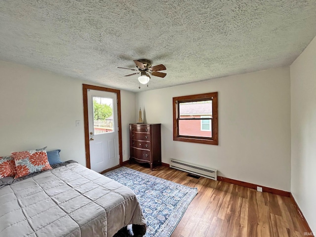 bedroom with a baseboard radiator, baseboards, wood finished floors, a ceiling fan, and a textured ceiling