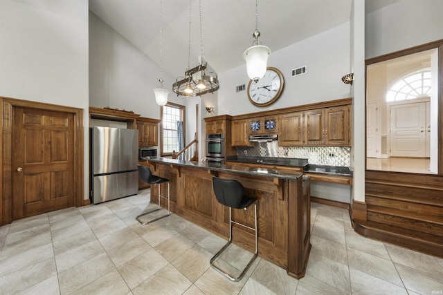 1711 Old Plank Rd, Newburgh, IN 47630 - kitchen with stainless steel appliances, high vaulted ceiling, dark countertops, a breakfast bar, and under cabinet range hood