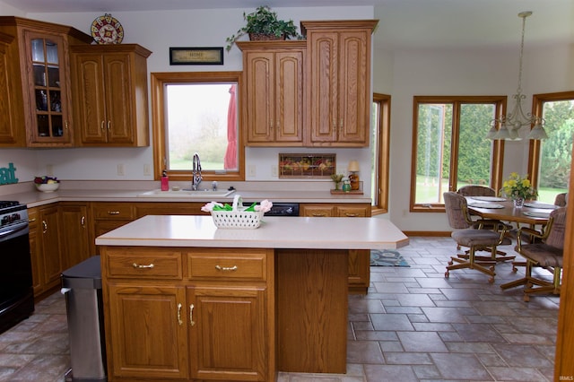 kitchen featuring stone tile floors, gas range oven, light countertops, and a sink