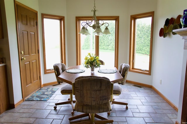 dining room with a wealth of natural light, stone tile flooring, and baseboards
