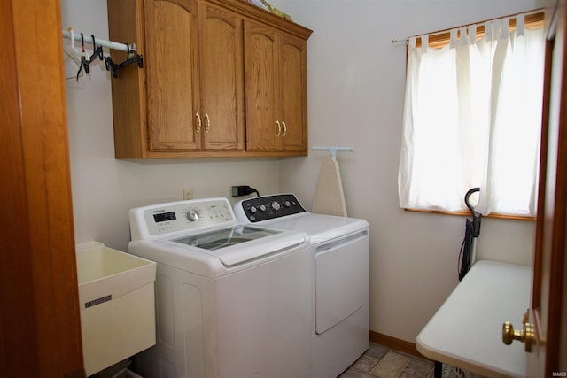 washroom with baseboards, a sink, cabinet space, and independent washer and dryer