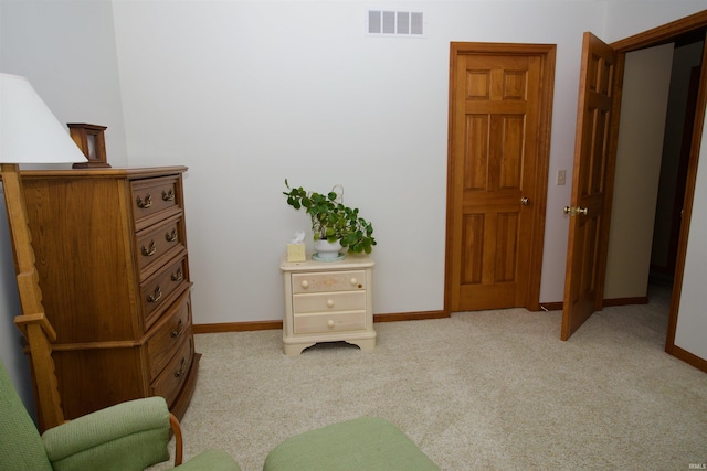 living area featuring baseboards, visible vents, and light colored carpet