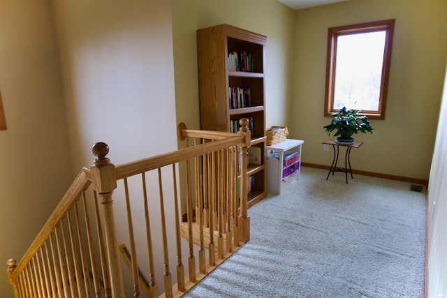 corridor with baseboards, an upstairs landing, and carpet floors