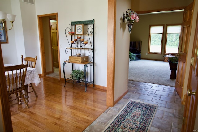 hallway featuring visible vents, stone tile flooring, and baseboards