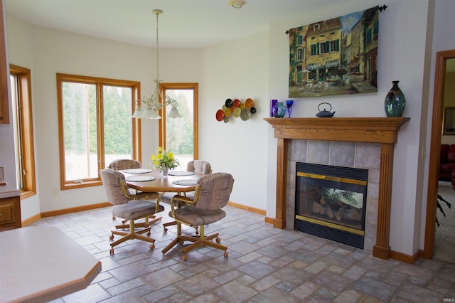 dining space with baseboards, stone tile flooring, and a fireplace
