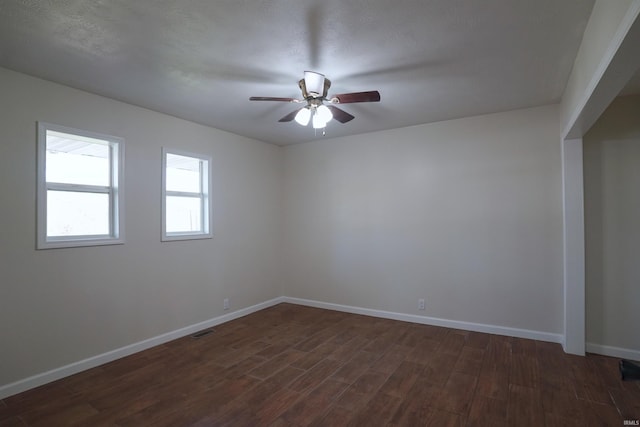 empty room with baseboards, visible vents, ceiling fan, and dark wood-style flooring