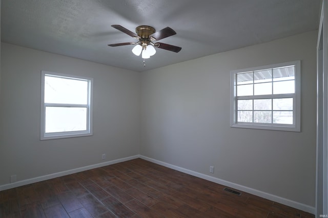 unfurnished room featuring baseboards, visible vents, a ceiling fan, and dark wood-type flooring