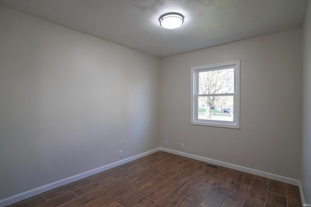 empty room featuring baseboards, visible vents, a textured ceiling, and dark wood-style flooring