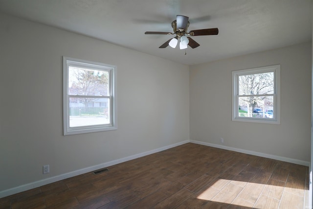 spare room featuring wood finished floors, a ceiling fan, visible vents, and baseboards