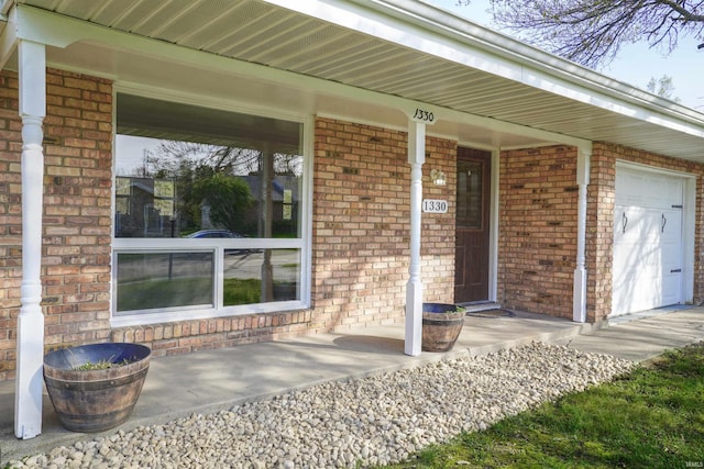 entrance to property with a porch and brick siding