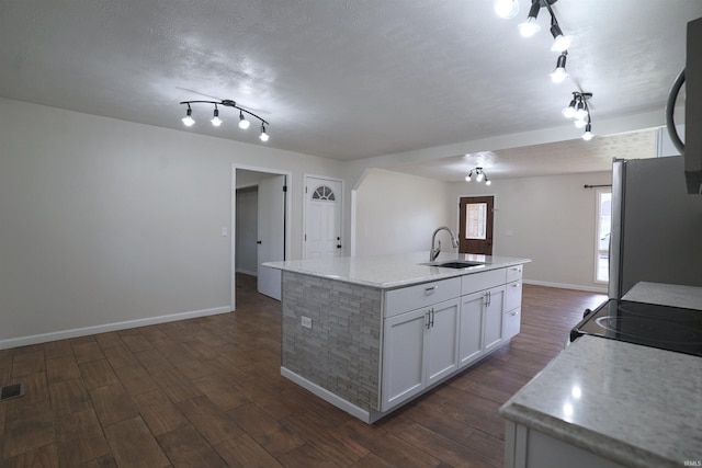 kitchen featuring a sink, rail lighting, freestanding refrigerator, and dark wood-style flooring