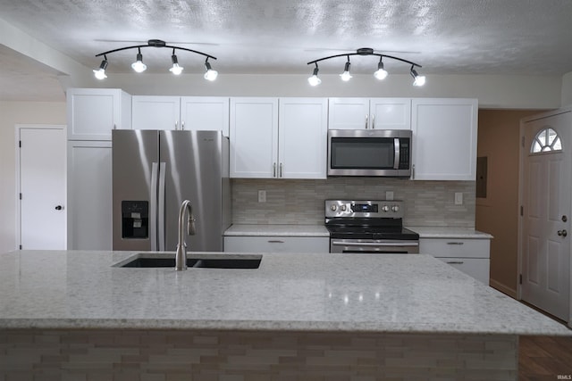kitchen featuring track lighting, white cabinets, stainless steel appliances, and a sink