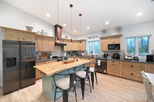 kitchen with a sink, stainless steel appliances, a kitchen bar, light wood-style flooring, and backsplash