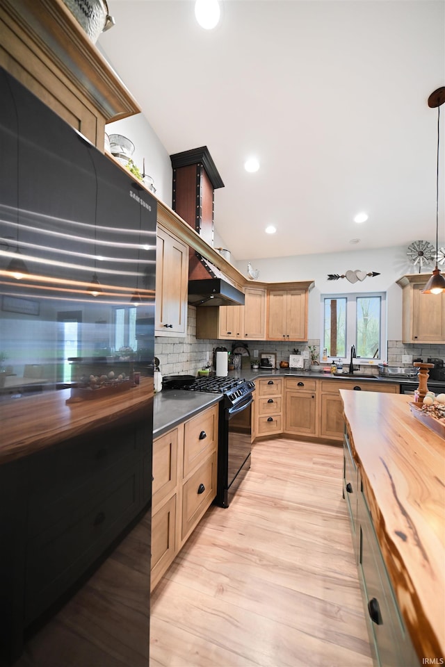 kitchen featuring black gas stove, dark countertops, backsplash, and light wood-style floors