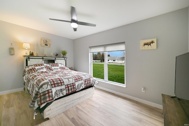 bedroom with light wood-style floors, a ceiling fan, and baseboards